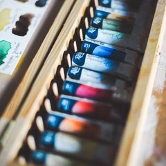 A long row of paint tubes in a wooden box
