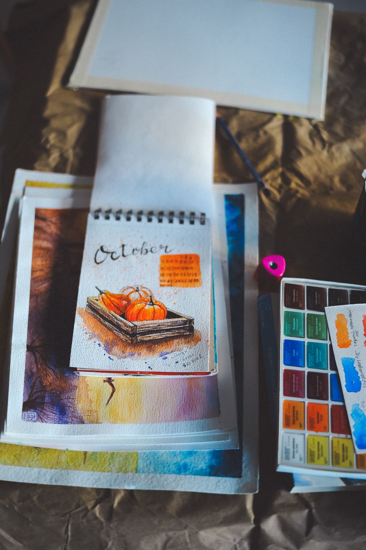 Sketchbook and watercolour palette on a studio desk