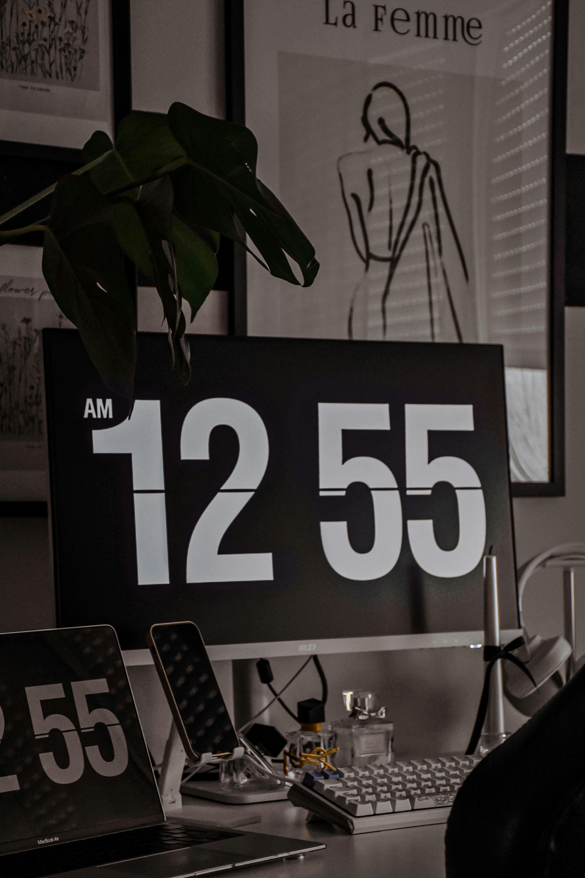Free A stylish home office setup featuring a digital flip clock showing 12:55 AM, capturing a techie atmosphere. Stock Photo