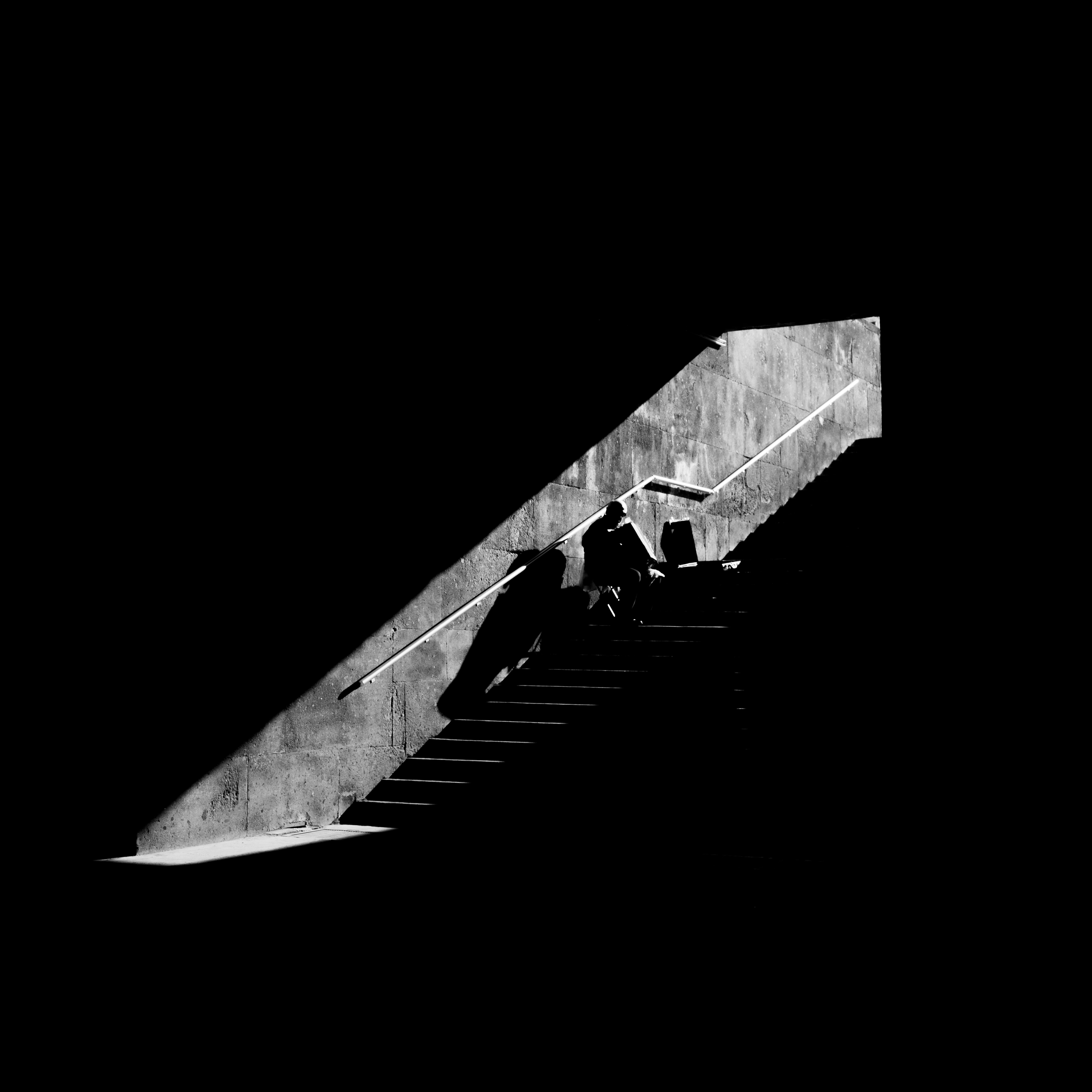 Dramatic black and white photo of people in silhouette on a staircase.