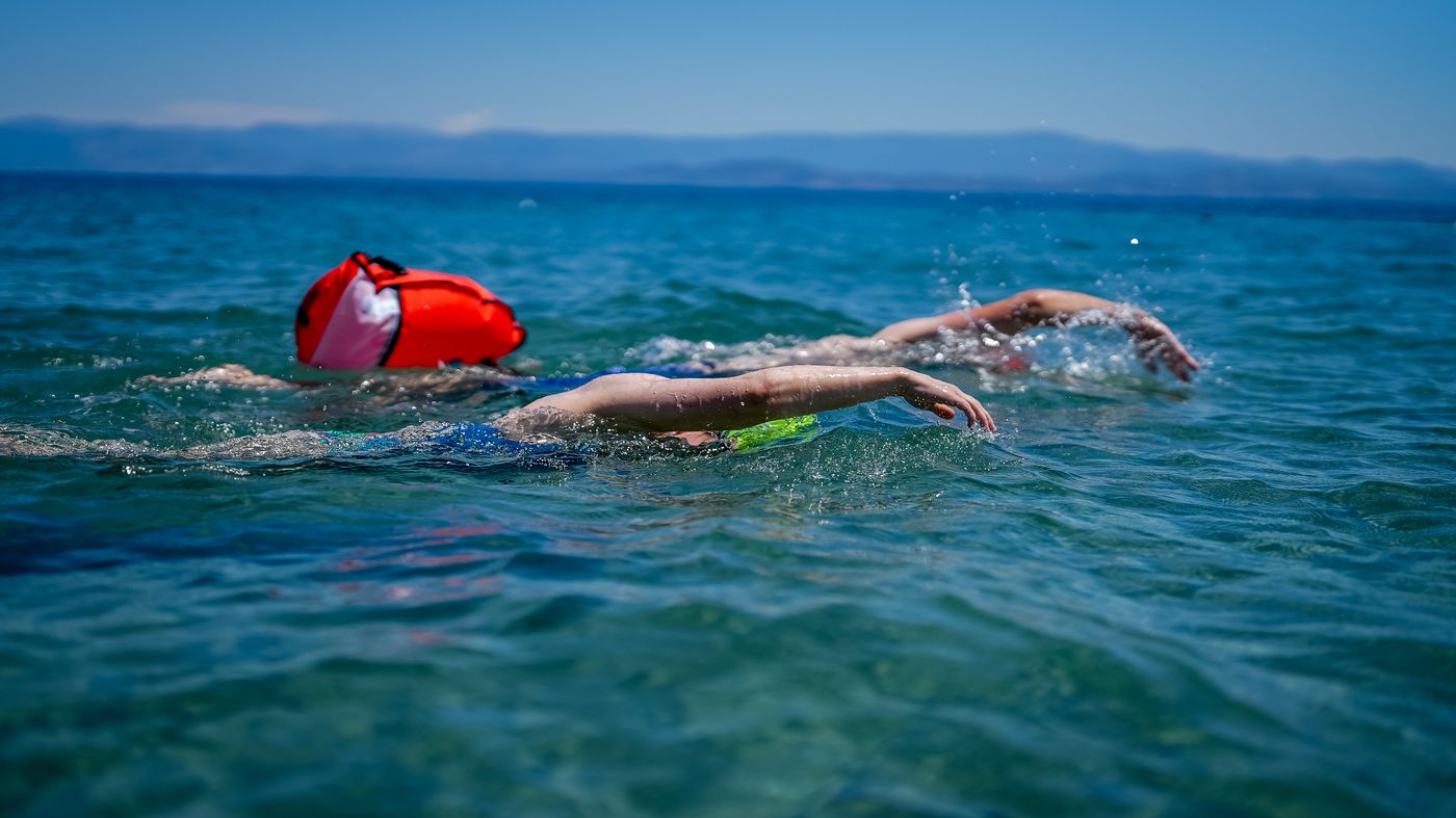 Open-water swimmers moving together across blue ocean water