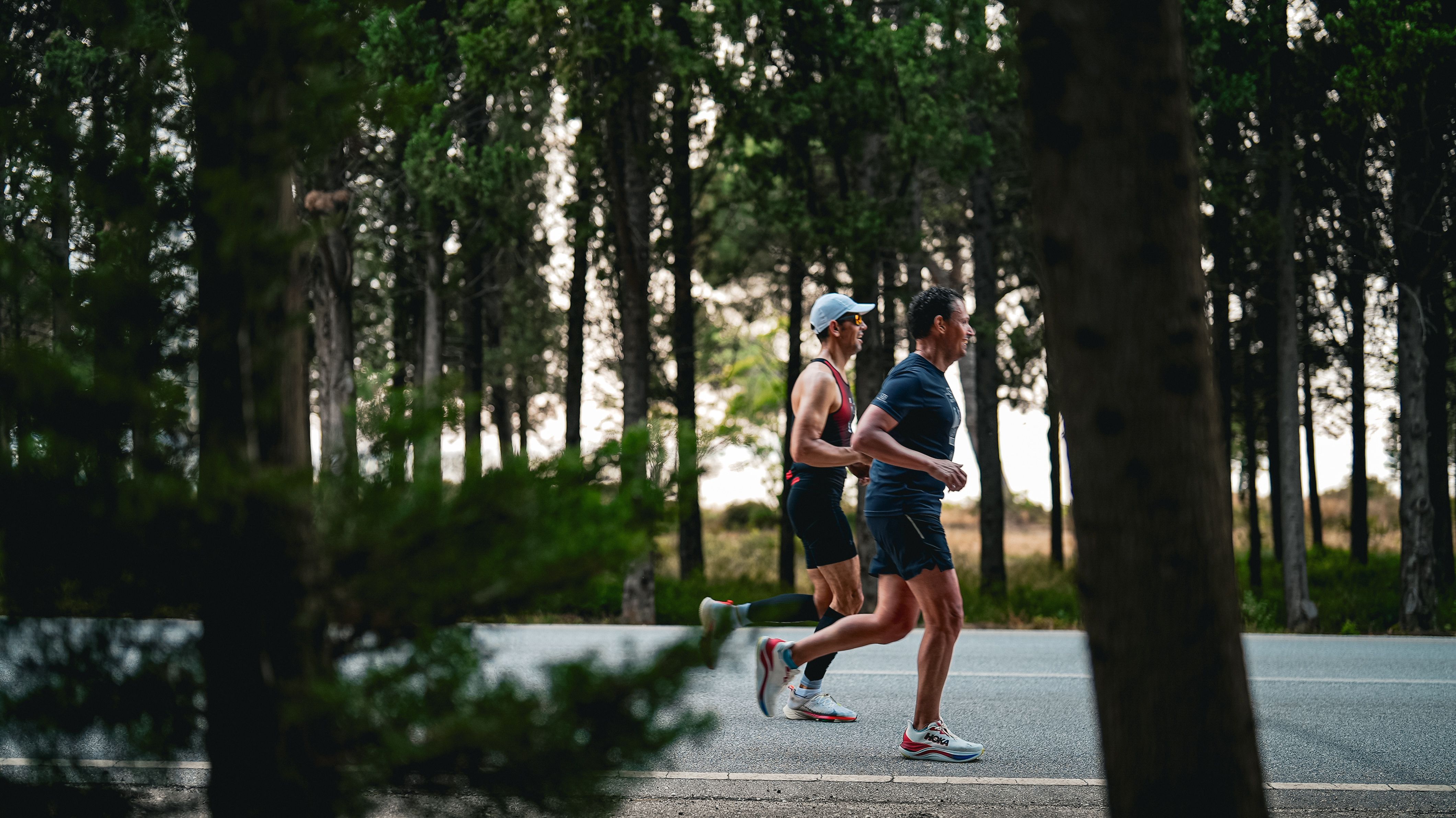Two runners on a tree-lined forest road