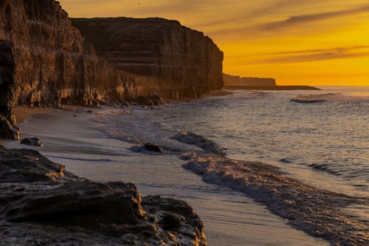 A breathtaking sunrise at Mar del Plata beach with dramatic cliffs and tranquil waves.