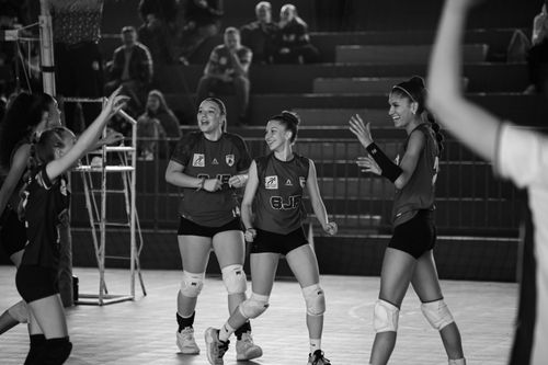 Free Black and white photo of a female volleyball team celebrating after a successful game. Stock Photo