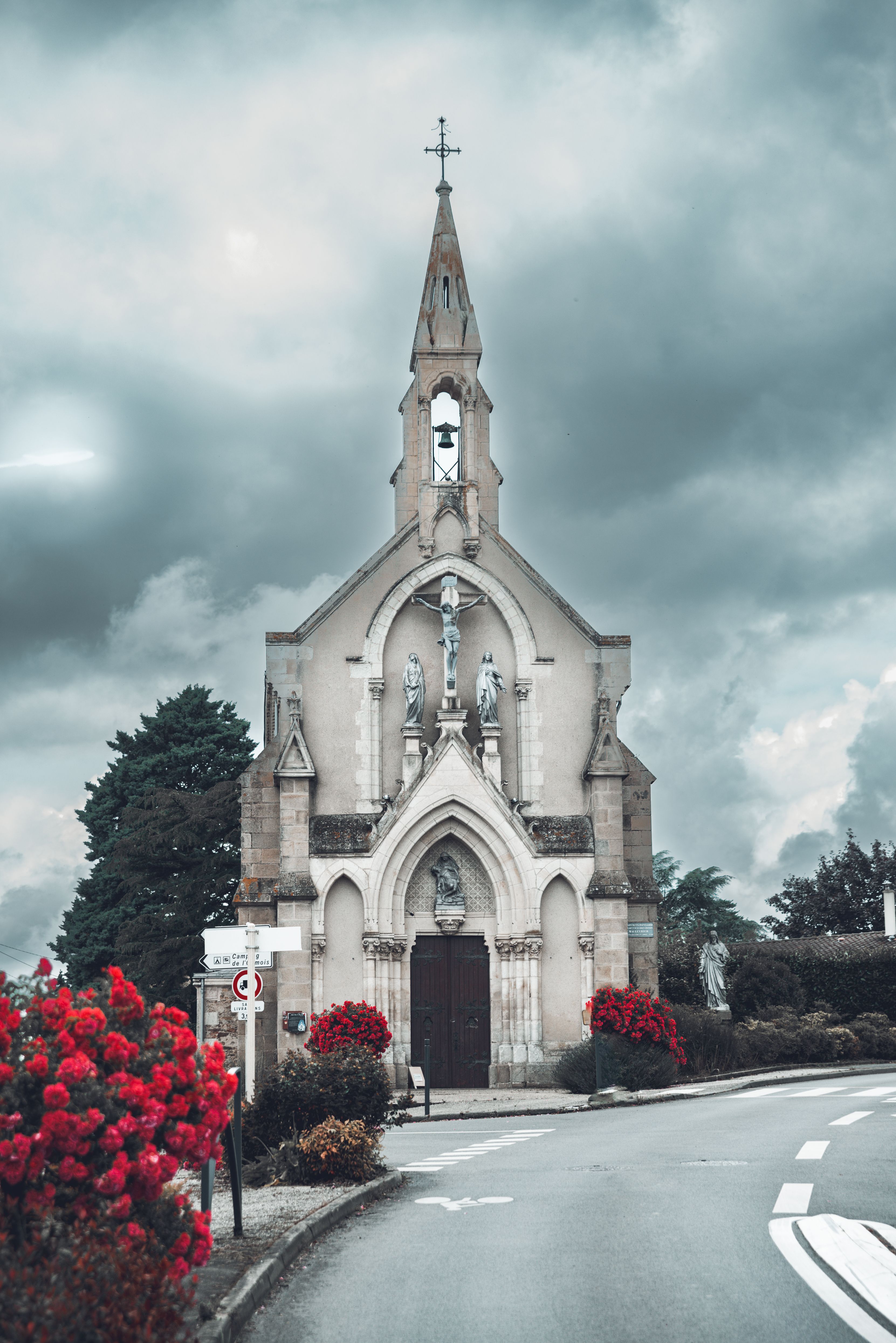 Gothic Church with Dramatic Sky and Red Flowers · Free Stock Photo