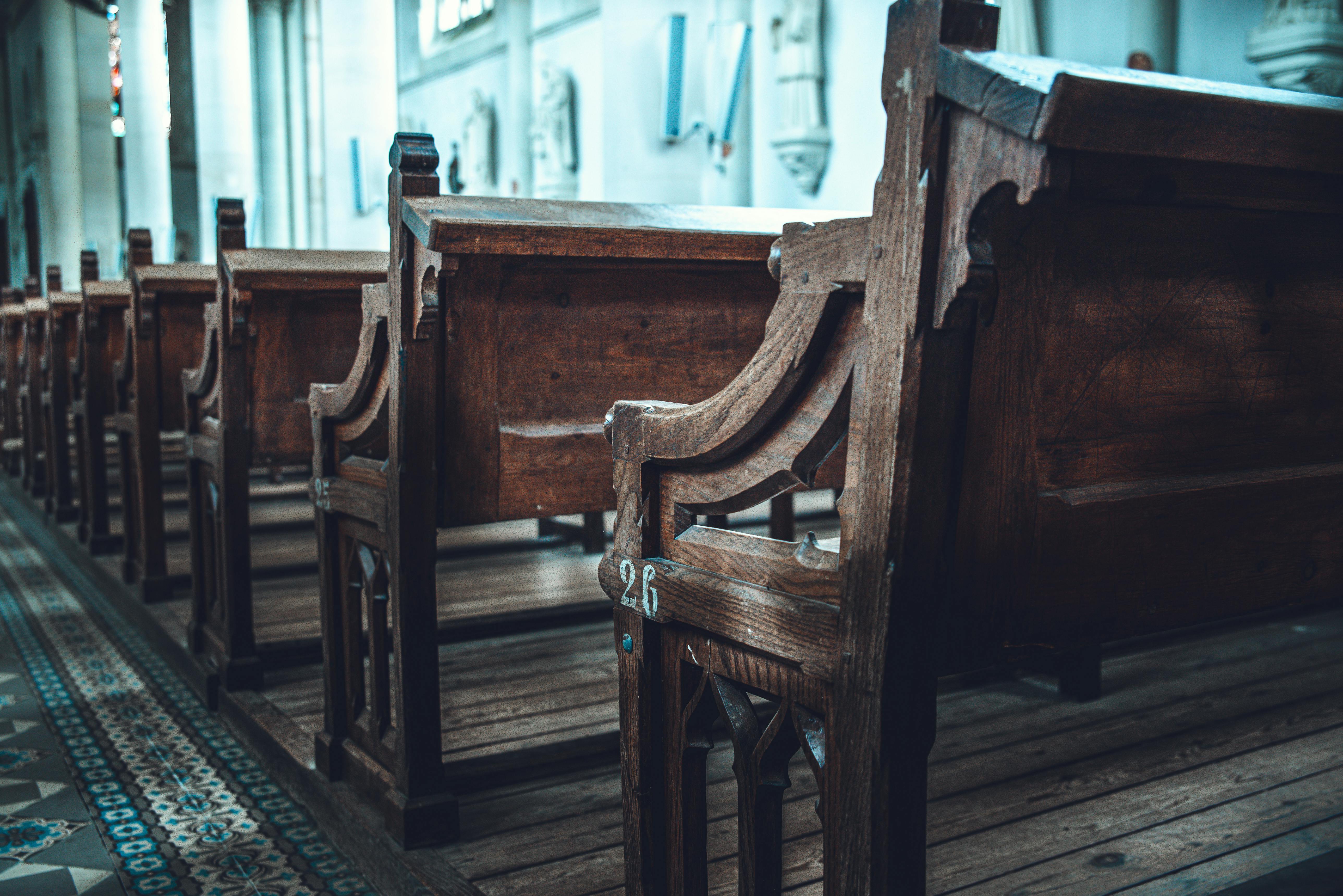 A serene view of traditional wooden church pews aligned in a sunlit interior.