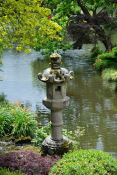 Tranquil scene of a Japanese garden with a stone lantern by a pond.