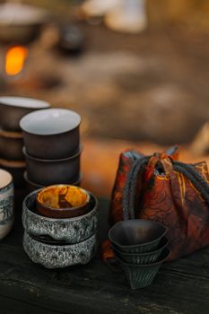 Artistic arrangement of rustic ceramic tea cups and colorful bag outdoors, ideal for tea lovers.