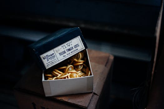 昏暗的场景中，一个打开的盒子里装着乳胶指套，展示着复古包装