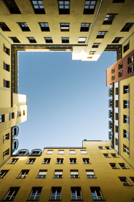 Modern symmetrical courtyard buildings in Berlin, Germany with blue sky.