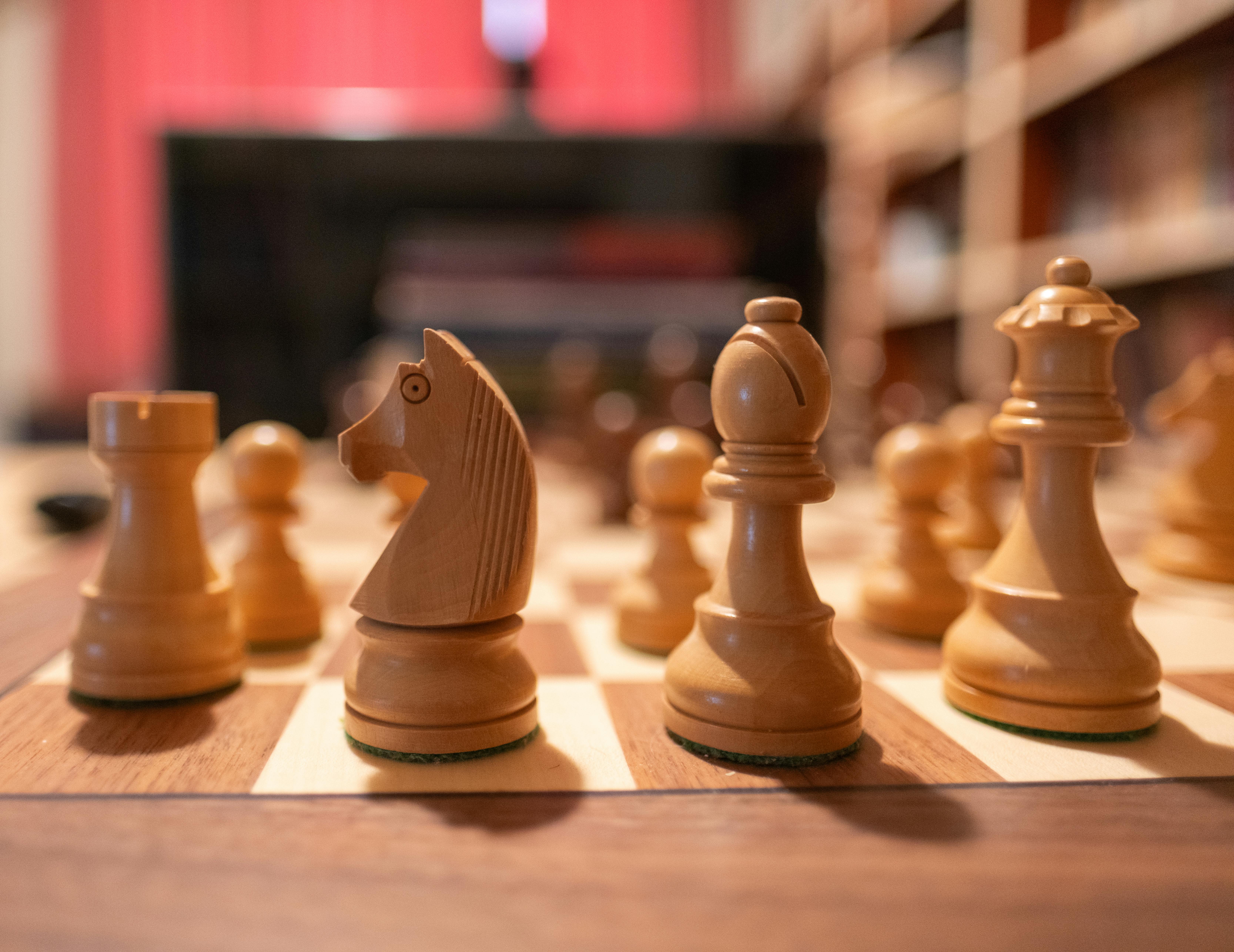 Close-up of wooden chess pieces on a chessboard in a cozy indoor setting.