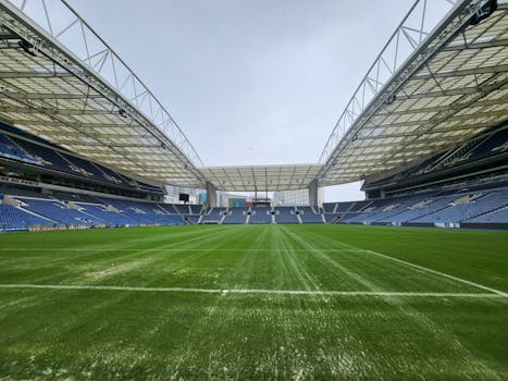 Panoramic view of an empty soccer stadium with vibrant green field and high roof structure.