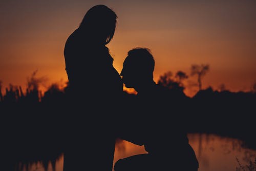 Silhouette Photo of Man Kissing His Wife Pregnant Stomach