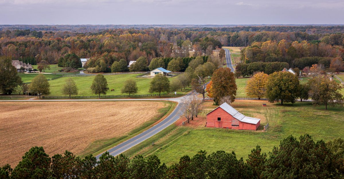 Aerial view of a picturesque farm landscape with fields and a red barn in fall.