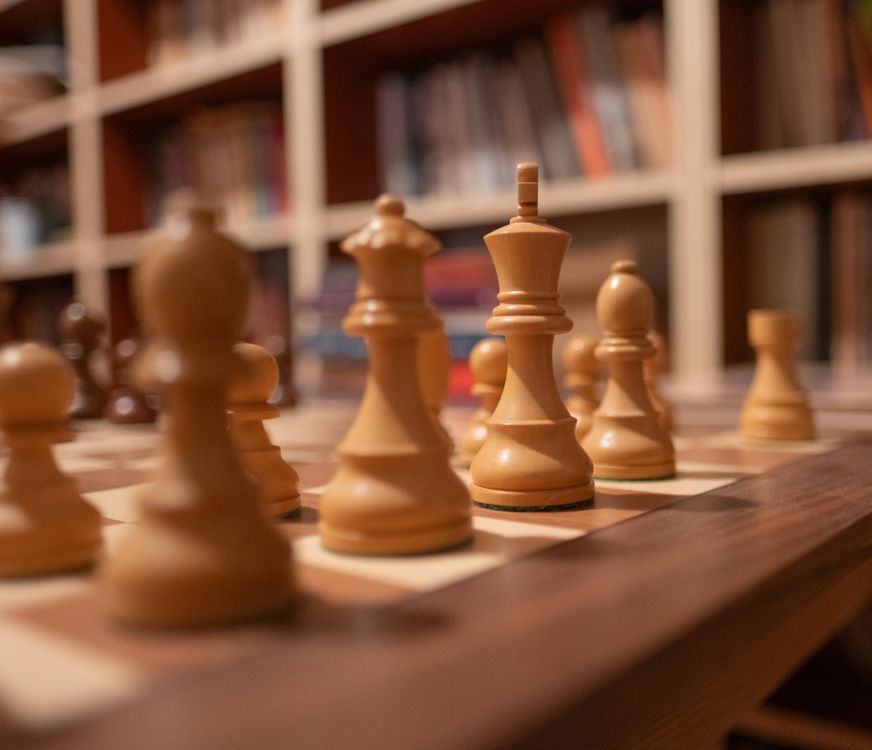 Wooden Chess Pieces on Chessboard in Library · Free Stock Photo