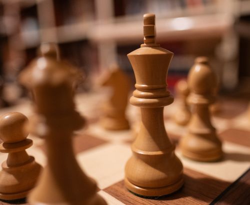 Free Detailed shot of wooden chess pieces on a chessboard in a dimly lit room. Stock Photo