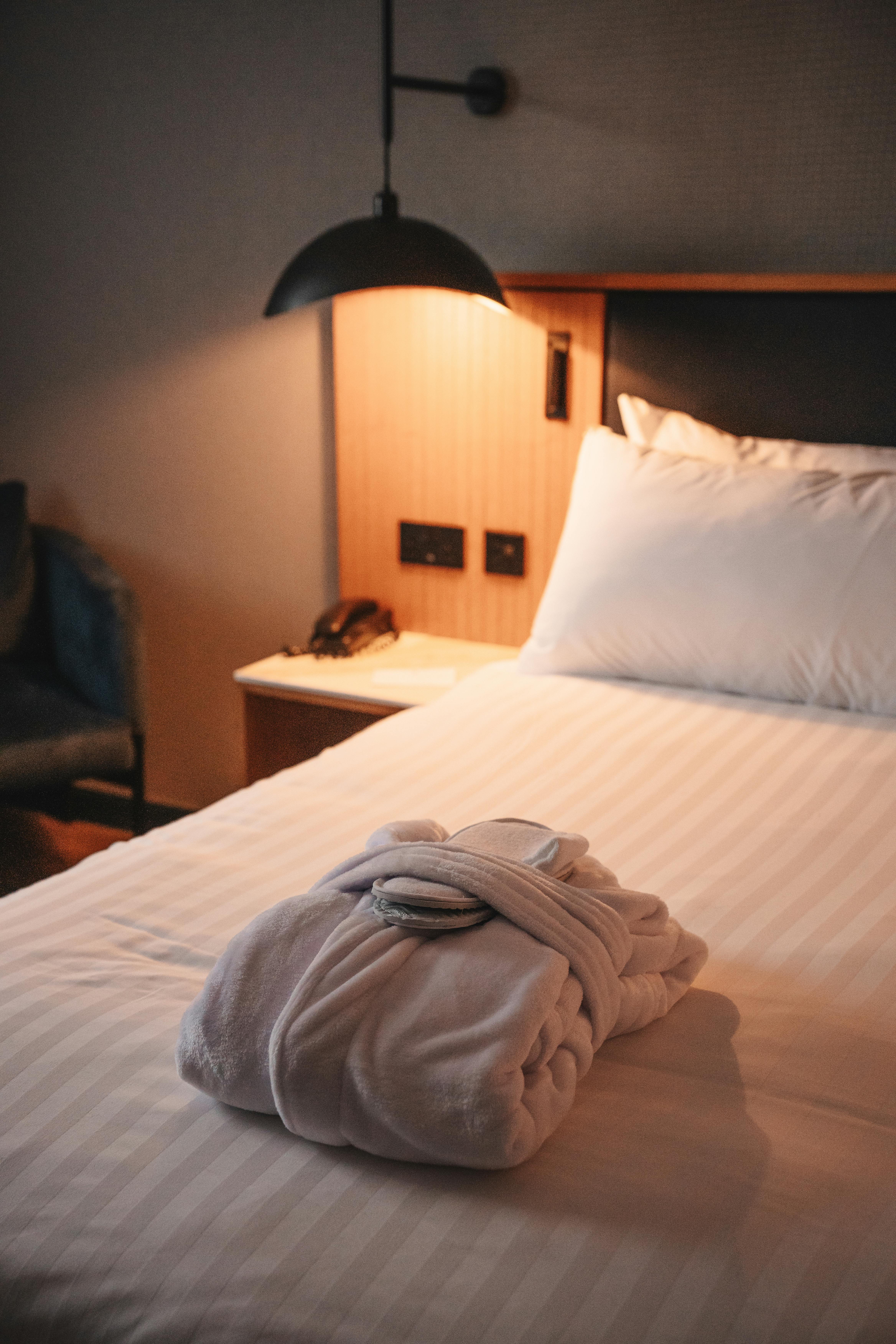 A cozy hotel room featuring a plush robe on the bed under warm lighting, epitomizing comfort and relaxation.