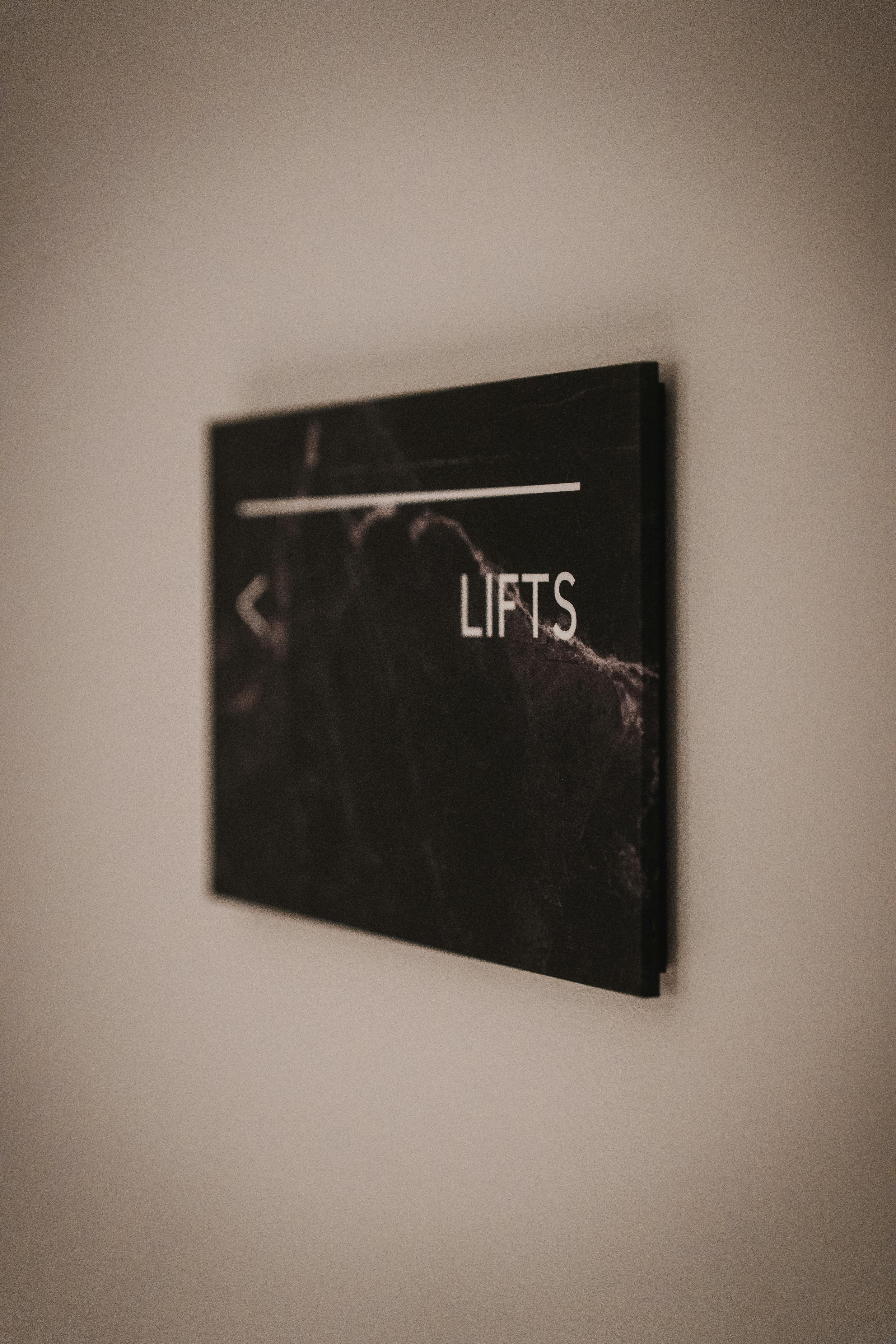 Gratis Elegante cartello in marmo nero che indica la direzione degli ascensori in un moderno spazio interno. Foto a disposizione