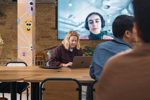 A diverse team in a modern office setting engages in a video conference.