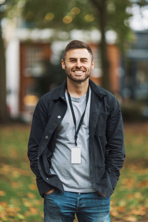 Free A cheerful man standing in an urban park surrounded by autumn foliage. Stock Photo
