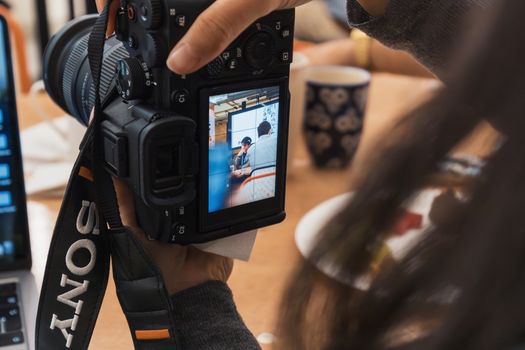 Close-up of a photographer taking pictures with a DSLR camera during an indoor workshop.