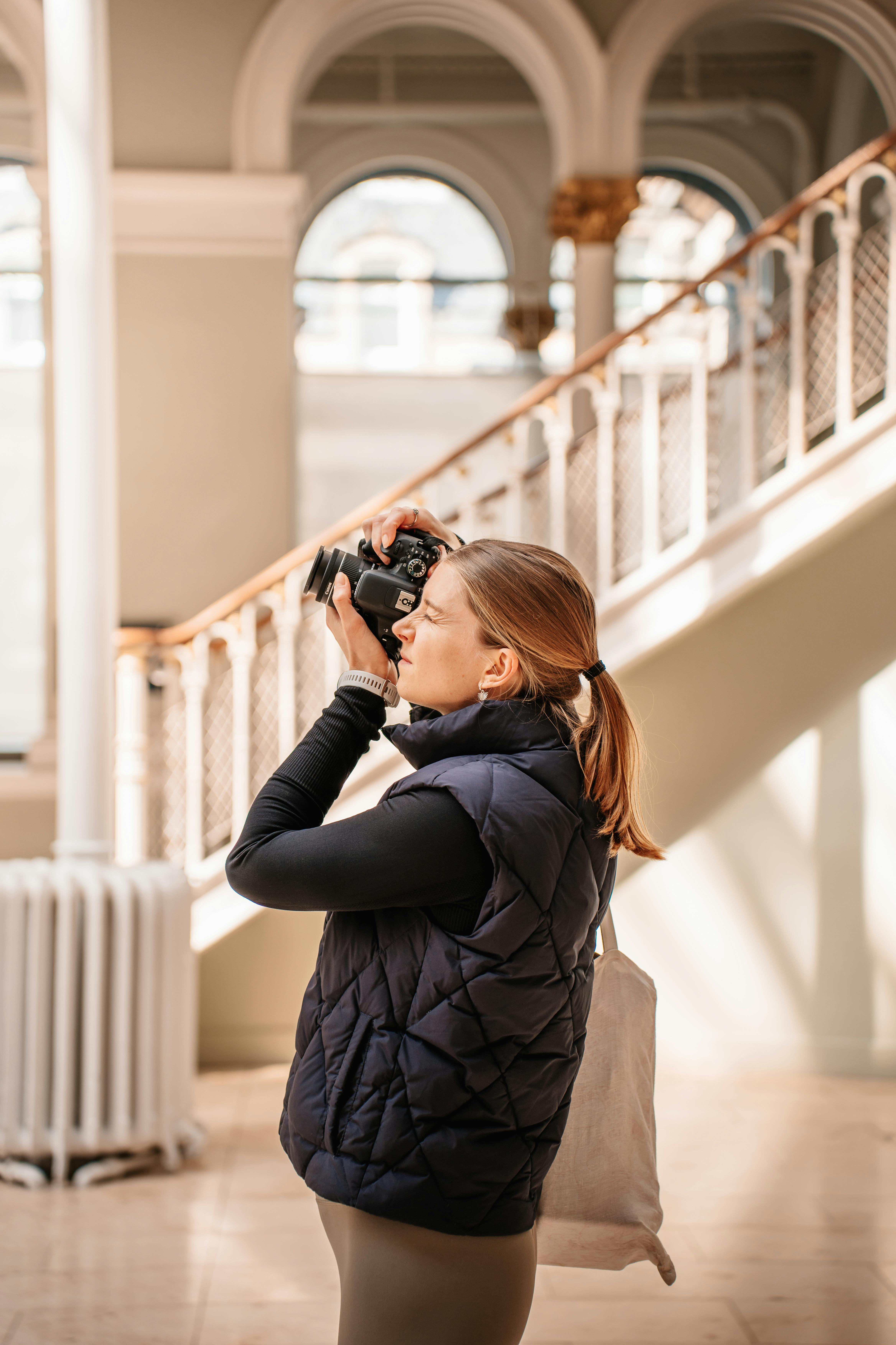A woman capturing indoor architectural beauty with her camera.