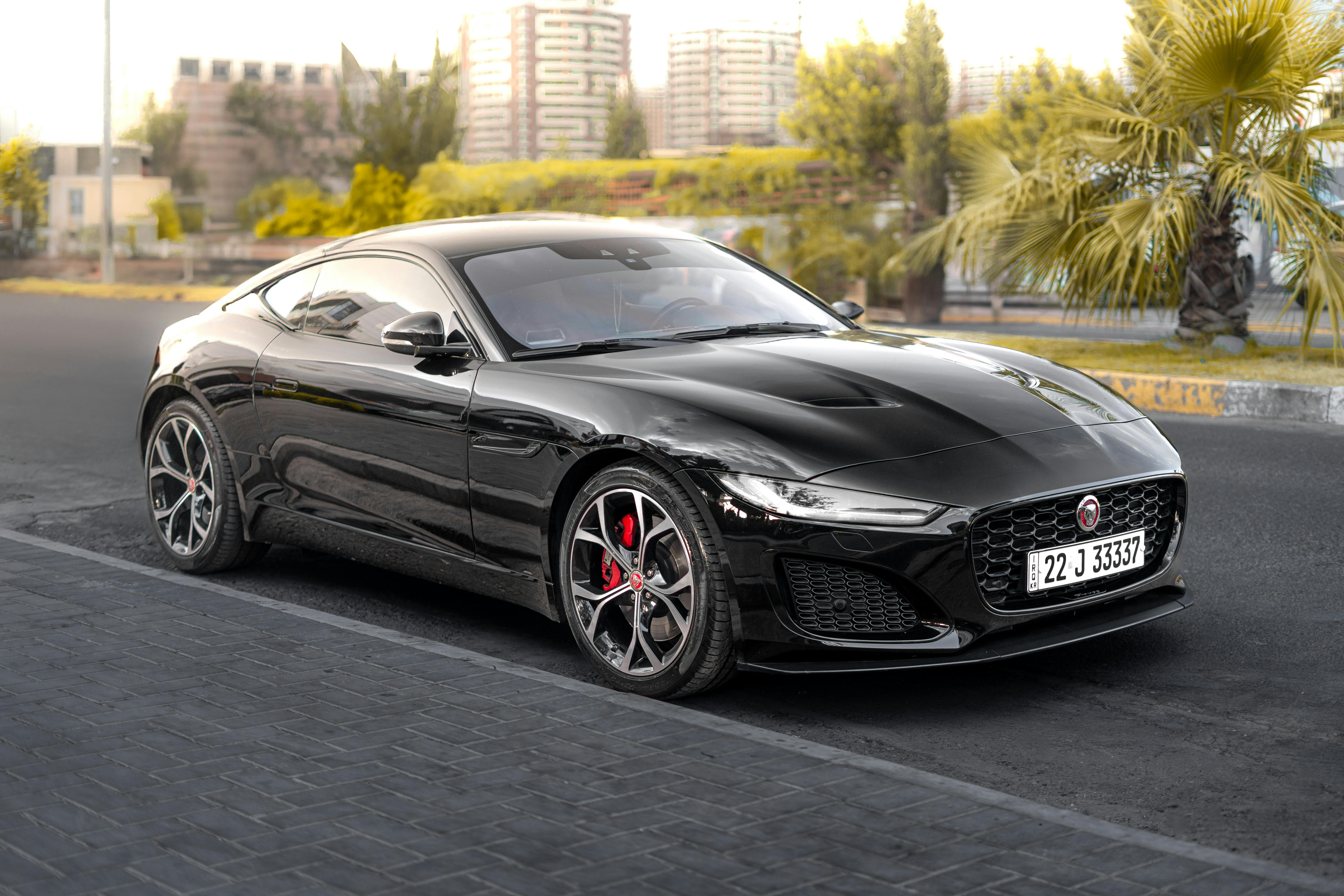 A luxurious black sports car parked against an urban city backdrop in Erbil, Iraq.