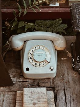 Classic rotary dial telephone on a rustic wooden table, showcasing vintage technology.