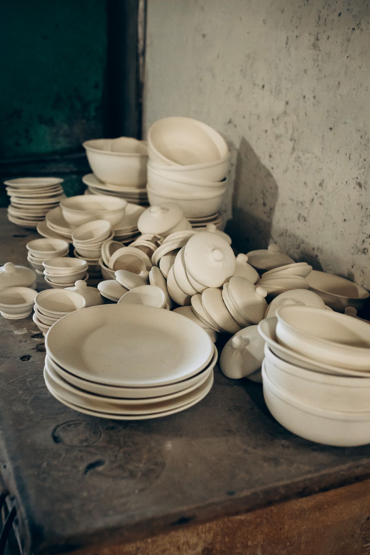 Unfinished porcelain ceramics stacked in a workshop — the production process unchanged in its essentials since Arita's first kilns in 1616