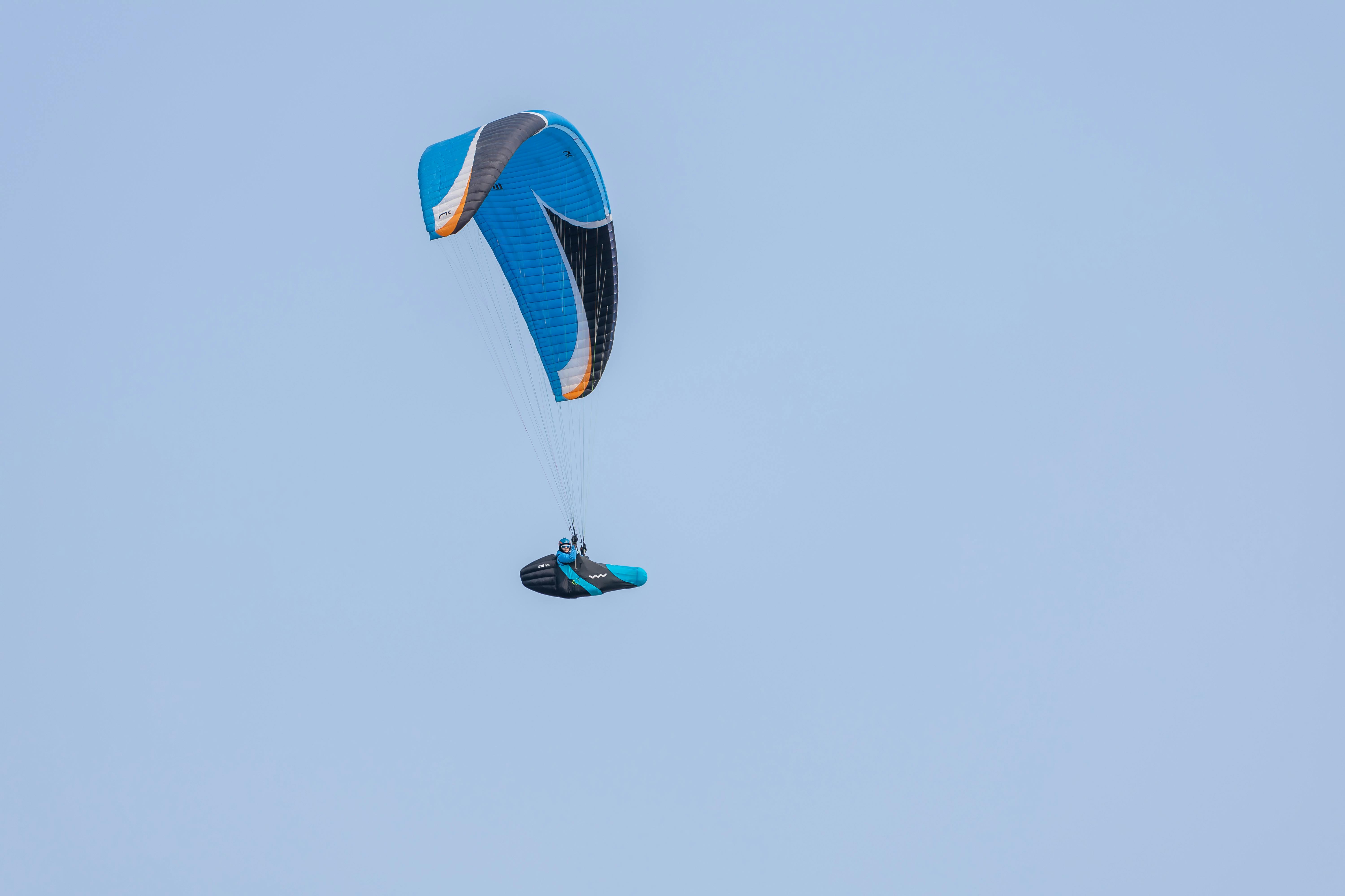 grátis Um parapente solitário voa alto em um céu azul claro, demonstrando aventura e liberdade. Foto profissional