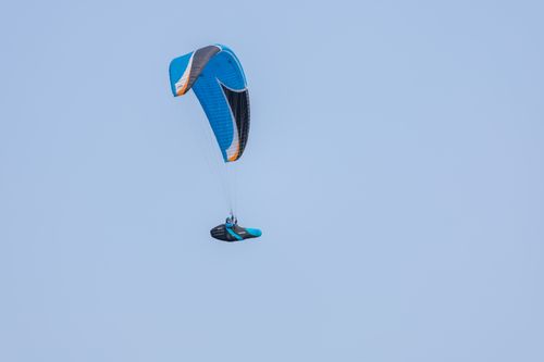 Free A lone paraglider flies high in a clear blue sky, showcasing adventure and freedom. Stock Photo