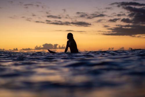 Free A silhouette of a surfer enjoying the tranquil waters of Waikiki at sunset in Hawaii. Stock Photo