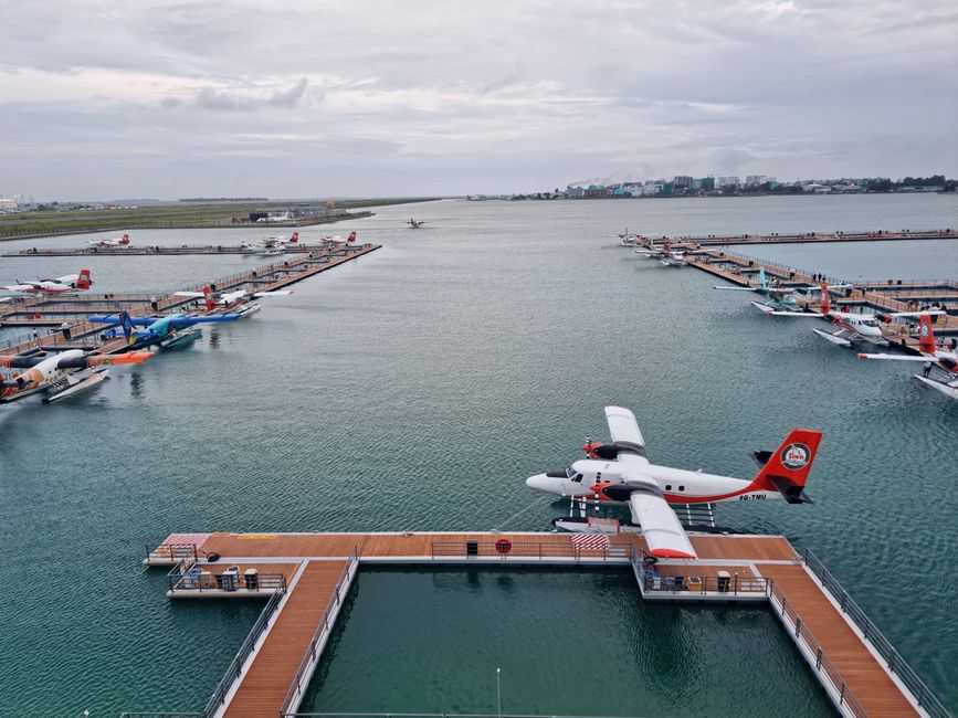 Busy seaplane terminal in the Maldives with passengers and aircraft
