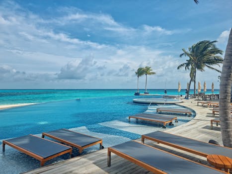 Relax by the stunning infinity pool at a luxury resort in the Maldives, surrounded by turquoise waters and palm trees.