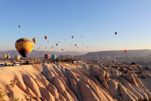 Free Colorful hot air balloons floating over Cappadocia's scenic rock formations during sunrise in Turkey. Stock Photo