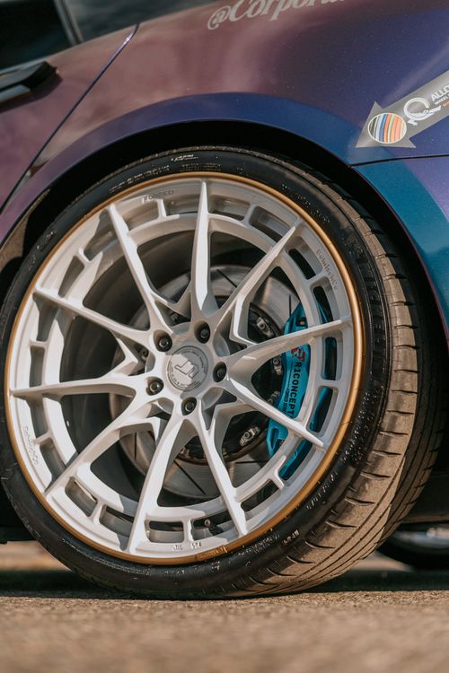 Free Detailed view of a car's custom alloy rim and tire on pavement. Stock Photo
