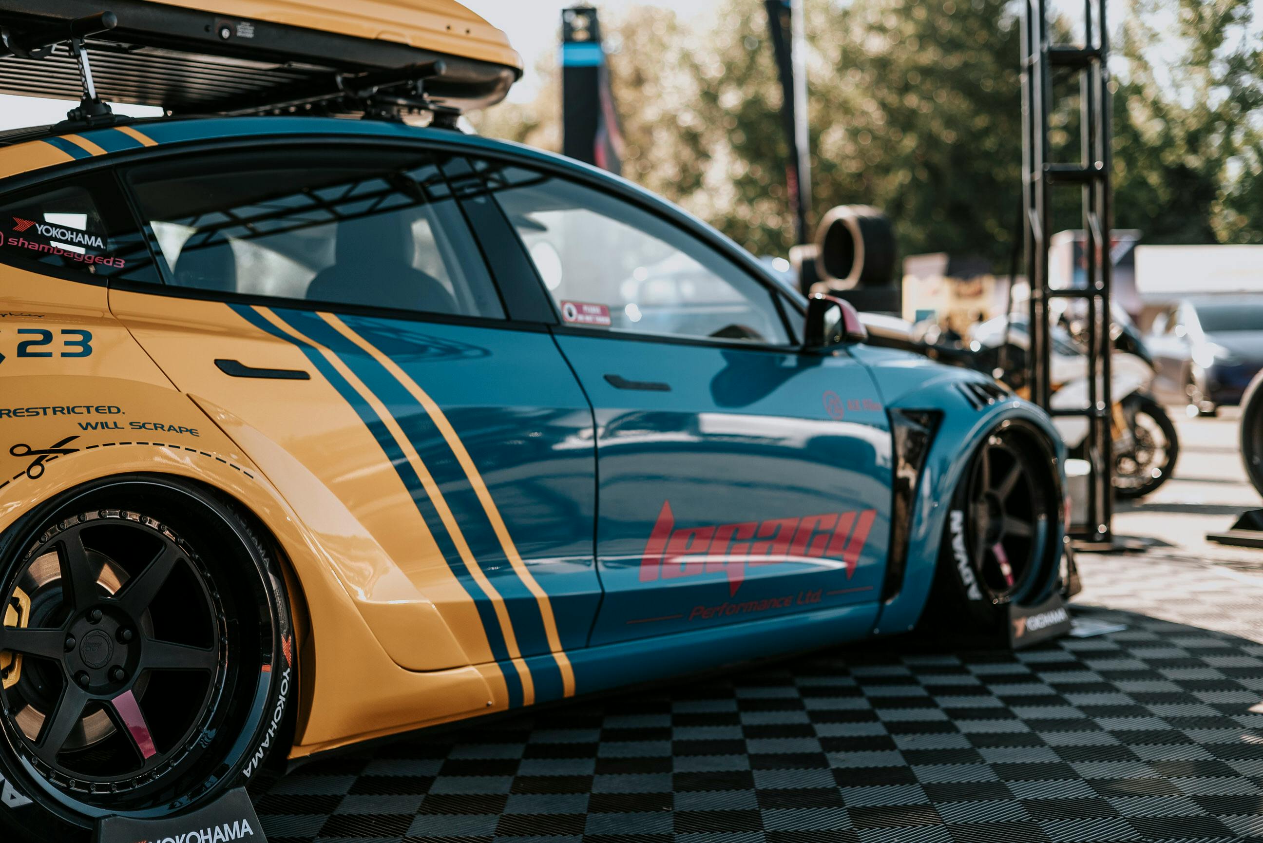 Custom blue and yellow racing car displayed at an outdoor auto show event.