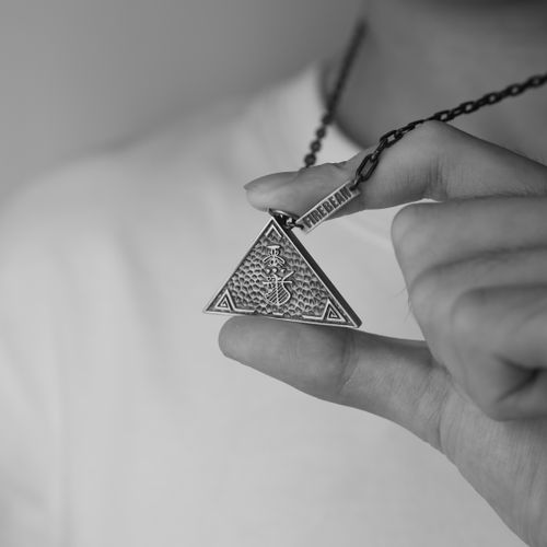Free Black and white photo of hand holding ornate triangle pendant necklace. Stock Photo
