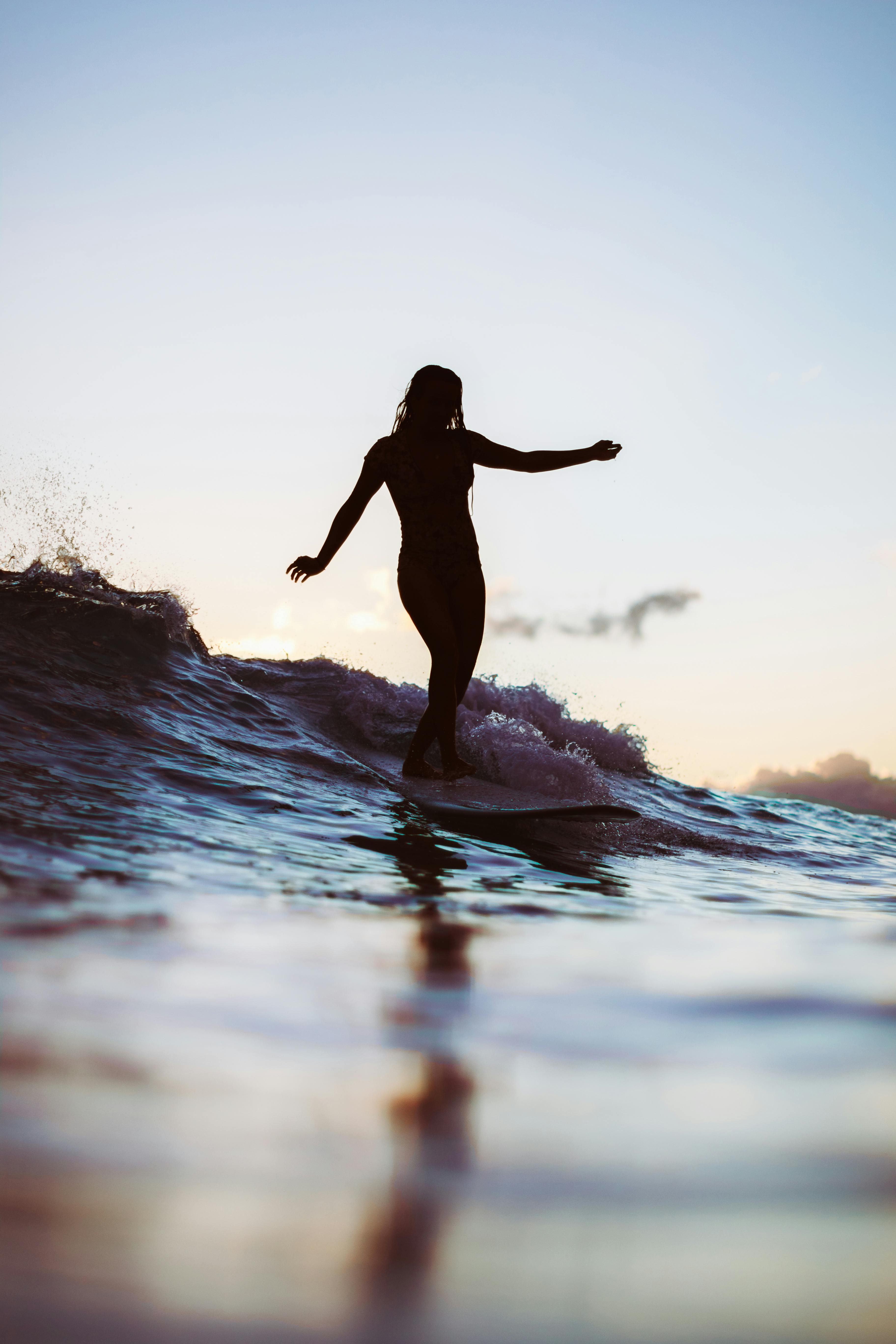 在夏威夷檀香山的日落时分，冲浪者们的剪影映照在平静的水面上