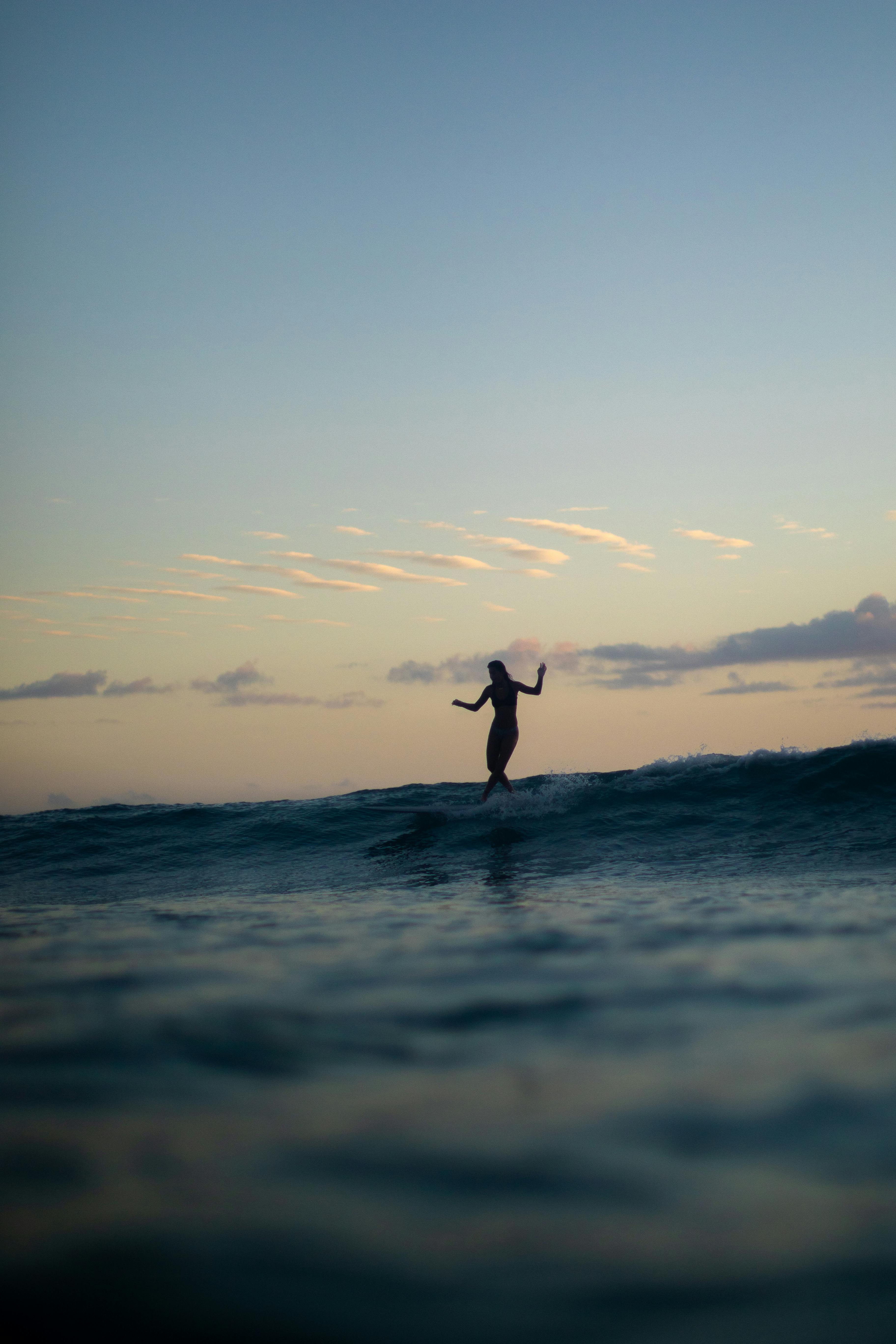 Silhouette of a person surfing at sunset in Honolulu, capturing the serene island atmosphere.