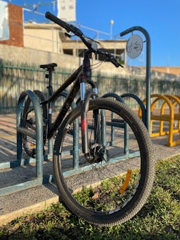 A mountain bike secured at a bike rack in a sunny urban area.