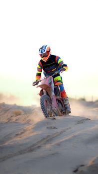 Dynamic shot of a motocross rider with vibrant gear racing over sand dunes.