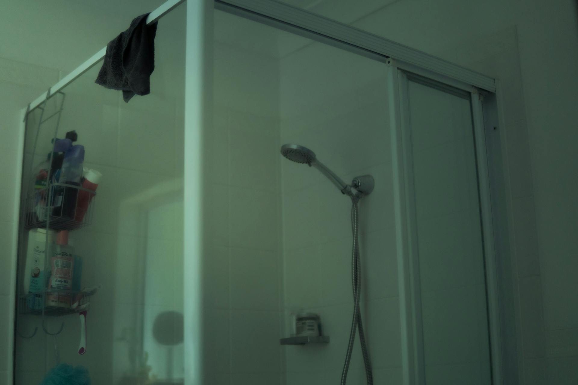 A contemporary bathroom shower with a glass door and wall-mounted showerhead.