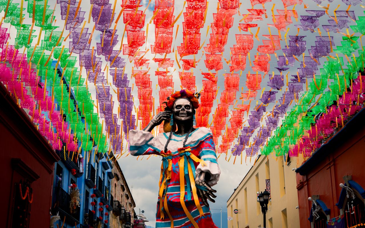 a vibrant display of colorful papel picado and a day of the dead statu