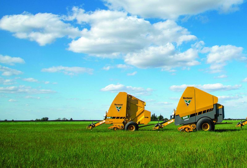 Vermeer hay balers on a grassy field under blue sky