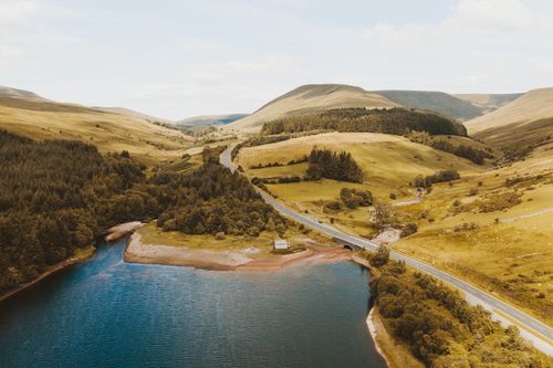 Free A breathtaking aerial view of a serene lake nestled among rolling hills and forests in a mountainous landscape. Stock Photo