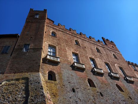 A stunning view of the historic brick castle in Montemagno, Piemonte against a clear blue sky.