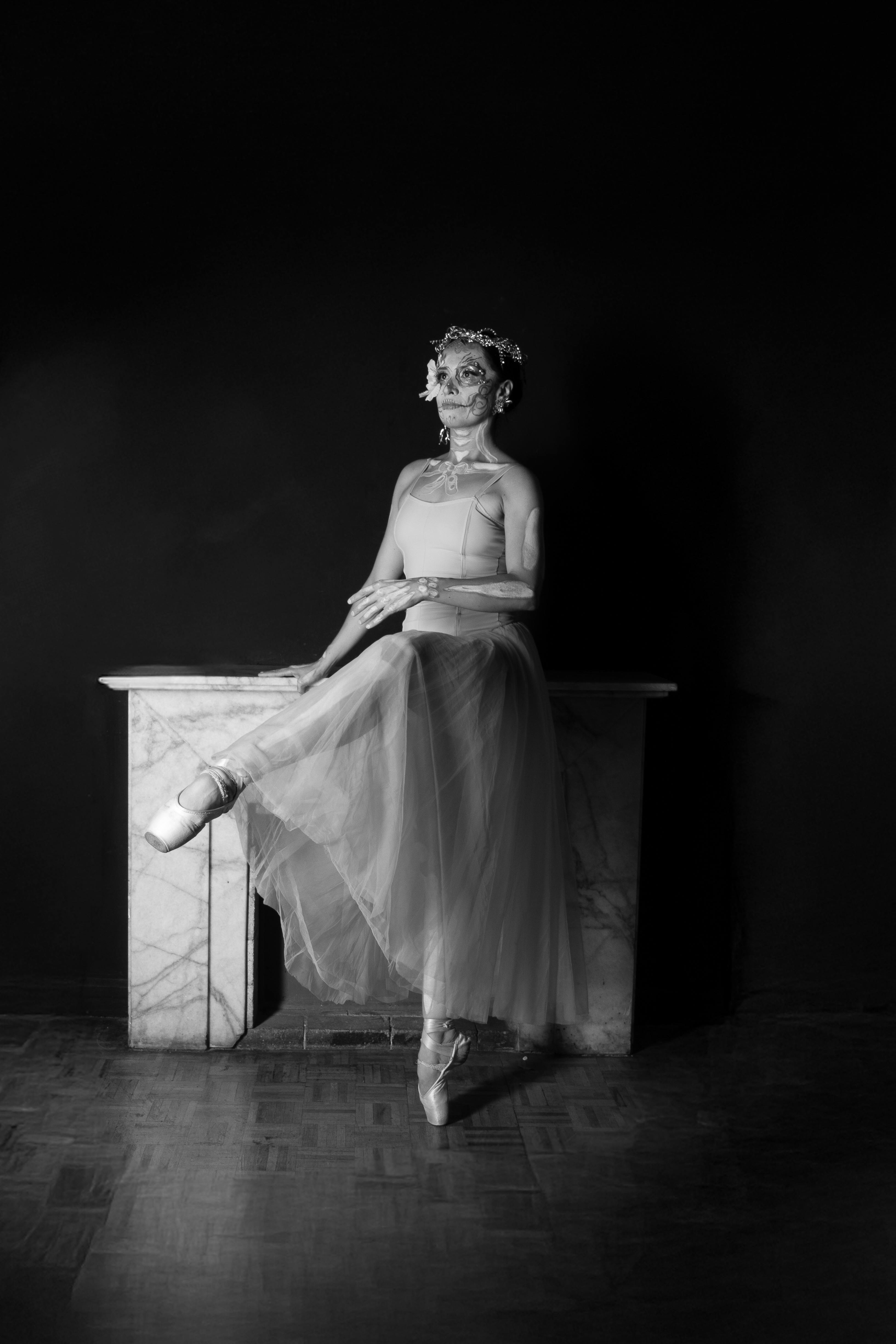 Black and white image of a Catrina ballerina with elaborate floral headdress, poised on pointe.