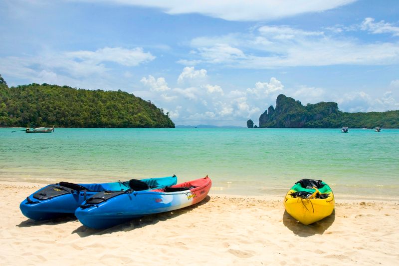 Kayaks de colores en una playa de aguas turquesas, material náutico en venta