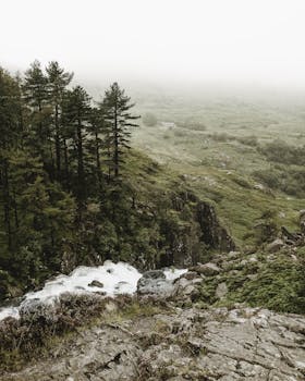 薄雾笼罩的山地景色宁静，瀑布倾泻而下